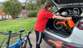 Person loading a folding e-bike into a car boot